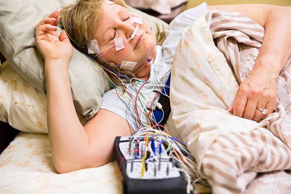Woman sleeping in a bed in the hospital with equipment attached during a sleep study. RM.  rr